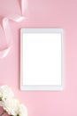 Minimal feminine flat lay with pink and white flower and tablet with empty screen. Styled mock up top view on pale peach