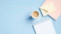 Minimal freelancer workspace with notebook, notepad, cup of coffee, pen, envelope on blue background. Flat lay, top view, copy Royalty Free Stock Photo