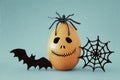 minimal and funny Halloween holiday concept. Orange egg with scary cute face, spiderweb, bat and spider on top. Royalty Free Stock Photo