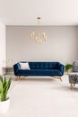 Minimal living room interior with a blue sofa and lots of empty space on the floor and on the background wall. Real photo. Royalty Free Stock Photo