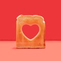 Minimal love concept. Arrangement made of one slice of toasted bread with a heart shaped hole in it. Red background