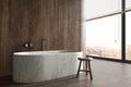 Minimal luxury bathroom with city view. Stone floor, wood tile wall and modern marble bathtub. Interior have large Royalty Free Stock Photo