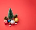 Minimal new year Christmas scene with tree, colorful baubles, presents and gift box on red pastel background Royalty Free Stock Photo