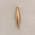 Minimal New Year concept in Nordic style, single bronze finial drop Christmas tree ornament flat lay on neutral beige