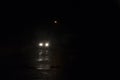 A minimal picture of car headlights underneath a street light on a dark rainy night
