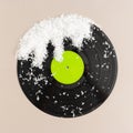 Minimal pop art holiday composition made with vinyl record with green label and snow against beige background. Creative retro Royalty Free Stock Photo