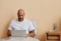 Adult black man using laptop in bed in morning Royalty Free Stock Photo
