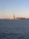 Minimal seascape view of the Statue of Liberty silhouette in the horizon, wide blue and yellow foggy sky in background, Staten