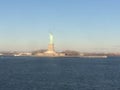 Minimal seascape view of the Statue of Liberty silhouette in the horizon, wide blue and yellow foggy sky in background, Staten