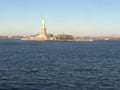 Minimal seascape view of the Statue of Liberty silhouette in the horizon, wide blue and yellow foggy sky in background, Staten