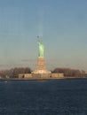 Minimal seascape view of the Statue of Liberty silhouette in the horizon, wide blue and yellow foggy sky in background, Staten