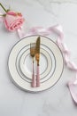 Minimal serving plate with tableware, flower and ribbon at white background