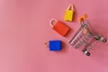 Minimal shoping online concept, Colorful paper shopping bag and trolley go down from floating pink background for copy space