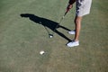 Minimal shot of woman playing golf in sunlight and aiming ball to hole Royalty Free Stock Photo