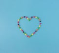 Minimal top view of shaped heart made of candies on blue background. Valentines day, birthday concept Royalty Free Stock Photo