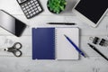 Minimal unisex workplace with tablet, notepad, smartphone, small succulent and accessories on a light wooden background.