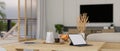 Minimal wood dining table with tablet and stuff over blurred minimal living room in the background Royalty Free Stock Photo