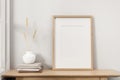 A minimal wood picture frame mockup on a wooden table against the white wall in a living room Royalty Free Stock Photo