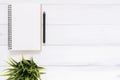 White office desk wooden table background with open mock up notebooks and pens and plant. Royalty Free Stock Photo