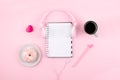 Minimal workplace with white blank notepad, pink headphones, heart, coffee cup and donut on pink background. Top view. Flat lay