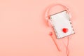 Minimal workplace with white blank notepad, pink headphones, heart, pencil on coral background. Top view. Flat lay Royalty Free Stock Photo