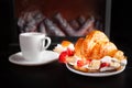 Minimalism, food on a background. Empty text space, mocap. fireplace, tea and croissant with strawberry cream and banana. A cozy Royalty Free Stock Photo