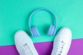 Minimalism. Music lover. Headphones, white sneakers on purple mint background. Top view. Flat lay.