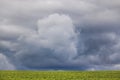 Minimalism photo of a dramatic cloud over a green field. Royalty Free Stock Photo