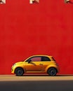 Minimalist background featuring a small car parked on a vibrant city street against a colorful wall.