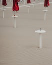 Minimalist beach scene with closed red umbrellas.
