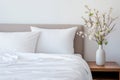 A minimalist bedroom accented by a bed with crisp white linens and a small vase of fresh flowers Royalty Free Stock Photo