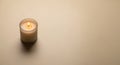 Minimalist beige candle on smooth surface creating warm ambient light Royalty Free Stock Photo
