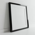 A minimalist black picture frame is set against a plain white wall and surface. The fra Royalty Free Stock Photo