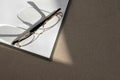 Minimalist business, branding, financial concept, eyeglasses on blank white paper sheet with aesthetic sunlight shadows