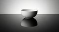 Minimalist ceramic bowl reflected on a polished surface with soft lighting Royalty Free Stock Photo