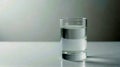 Minimalist Clear Glass of Water on Reflective White Surface With Neutral Gray Background Emphasizing Simplicity and Clarity Royalty Free Stock Photo