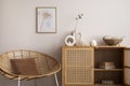 Minimalist composition of cozy and domestic space of living room with rattan commode, armchair, mock up poster frame, decoration, Royalty Free Stock Photo