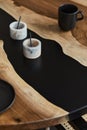 Minimalist composition on the design wooden and epoxy table with black cups and spoon, marble vessel. Modern dining room interior. Royalty Free Stock Photo