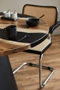 Minimalist composition on the design wooden and epoxy table with black teapot, cups and spoon. Modern dining room interior.