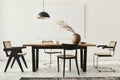 Minimalist composition of dining room interior with wooden table, design chairs, dried flowers in a vase, black pendant lamp, art. Royalty Free Stock Photo