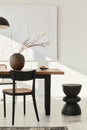 Minimalist composition of dining room interior with wooden table, design chairs, dried flowers in a vase, black pendant lamp, art. Royalty Free Stock Photo