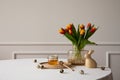 Minimalist composition of easter dining room interior with copy space, round table, vase with tulips, easter bunny sculpture,