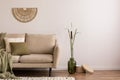 Minimalist composition of elegant and outstanding space with beige sofa, boucle rug, vase, green plaid, decoration and elegant