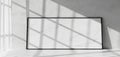 Blank picture frame leaning against a wall with dramatic sunlight and shadow patterns Royalty Free Stock Photo