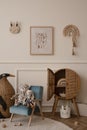 Minimalist composition of kid room interior with mock up poster frame blue armchair, plush toys, wooden blocks, rattan sideboard,