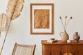 Minimalist composition of living room with brown mock up picture frame, plant, retro armchair, dried tropical leaf, decoration. Royalty Free Stock Photo