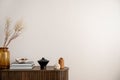 Minimalist composition of living room interior with copy space, wooden commode, vase with dried flowers, candle, black books and Royalty Free Stock Photo