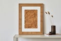 Minimalist composition of living room interior with mock up poster frame, beige commode, retro vase and personal accessories.