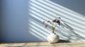 Minimalist decor with striped shadows, ceramic vase with dried flora, and sleek bowl against teal backdrop.