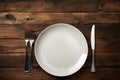 Minimalist dining Clean plate, fork, knife on weathered wooden table